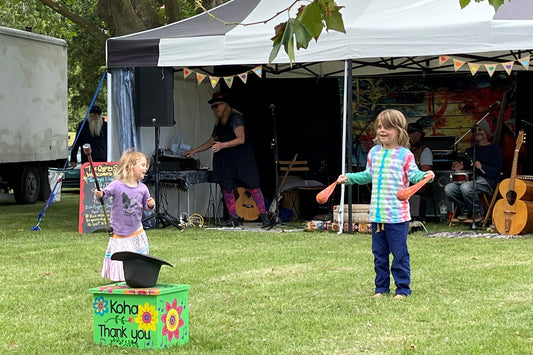 Two children play with poi and spin staff at a fair