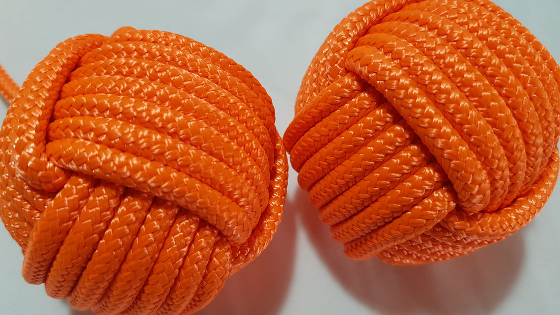 A close up of two monkey fist knots made from orange rope