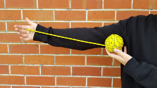 A person holds a yellow poi against their black sleeve to show how long a poi should be
