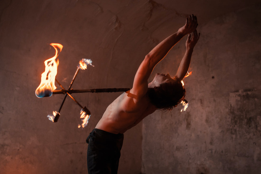 A man stands leaning back with his arms above his head and a fire dragon staff rolling down his chest