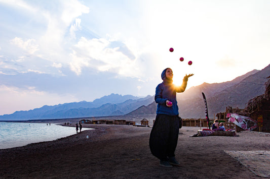 A man juggles three juggling clubs with blue sky in the background