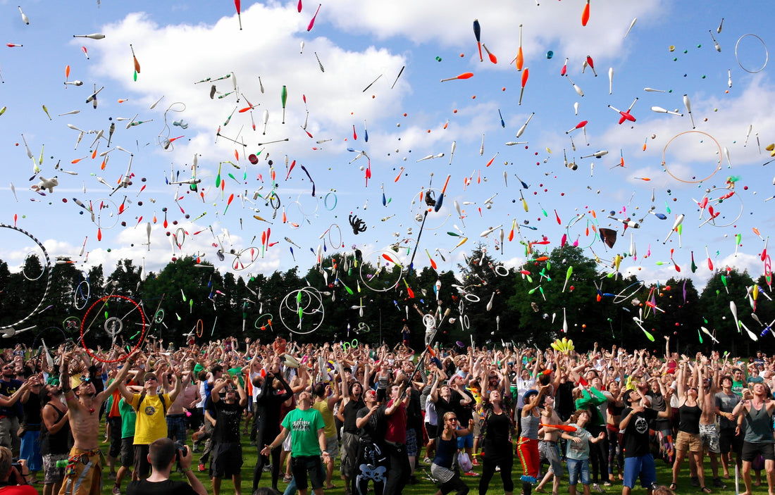 A large group of people throw into the air juggling rings, juggling balls, juggling clubs, hula hoops, spin staff and other flow props